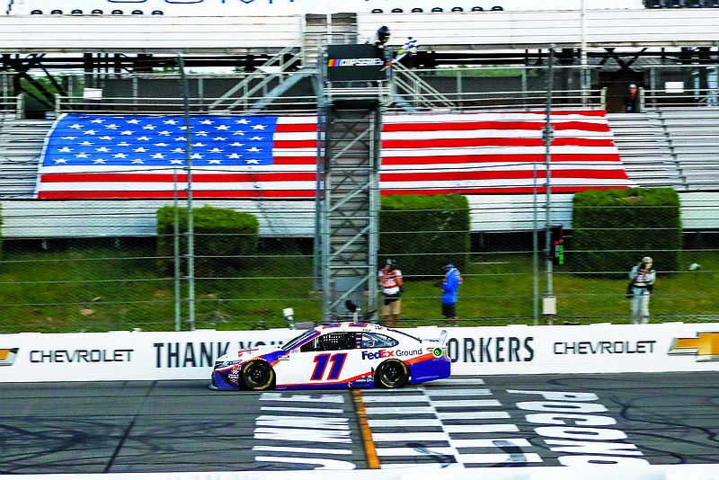 Denny Hamlin gets the checkered flag as he crosses the finish line to win Sunday's NASCAR Cup Series race at Pocono Raceway in Long Pond, Pa.