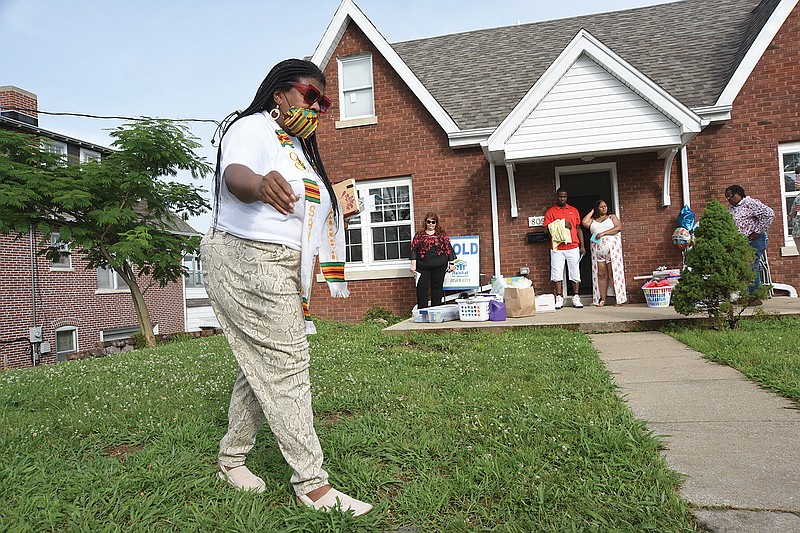 The Rev. Cassandra Gould sprinkles holy water on the ground in front of Reggie Lewis Jr. and Akisha Pinnell's new home.