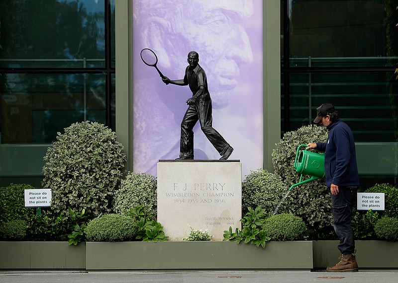 A gardener waters the plants alongside a statue of former Wimbledon Champion Fred Perry on Monday at the All England Lawn Tennis Club in Wimbledon in London.
