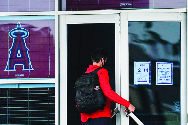 An Angels employee enters Angels Stadium on Wednesday in Anaheim, Calif. The Angels and other Major League Baseball teams will report to their respective facilities for training this week, amid the coronavirus pandemic.