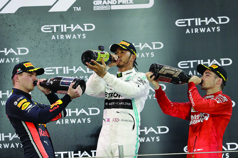 In this Dec. 1, 2019, file photo, Mercedes driver Lewis Hamilton (center) celebrates on the podium after wining the Emirates Formula One Grand Prix as Red Bull driver Max Verstappen (left) and Ferrari driver Charles Leclerc look on at the Yas Marina racetrack in Abu Dhabi, United Arab Emirates. Four months after the opening race was called off amid last-minute pandemonium the Formula One season finally gets underway this weekend in Austria.