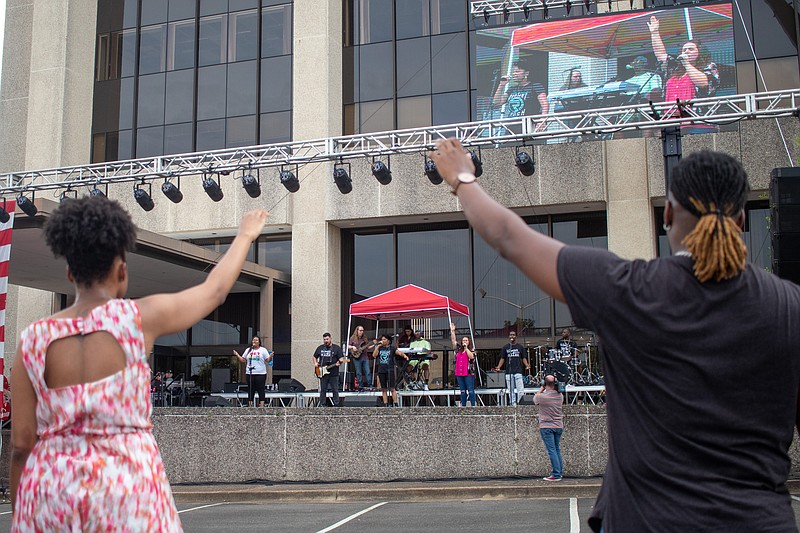 Attendees raise their hands in worship Saturday during Freedom Fest at the former Regions bank building in downtown Texarkana, Arkansas. The event also featured a snow cone truck, T-shirt stand and basketball hoops. (Photo by Sara Vaughn)
