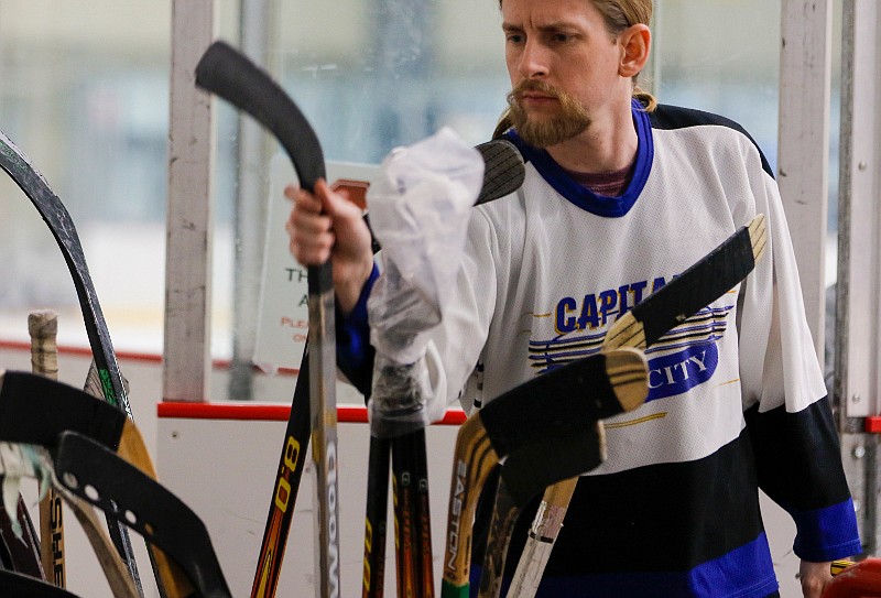 Chad Brown, as hockey program director for JC Parks, pulls out a hockey stick from a bin to hand to a child during a hockey camp on Wednesday, July 1, 2020, at Washington Park Ice Arena.