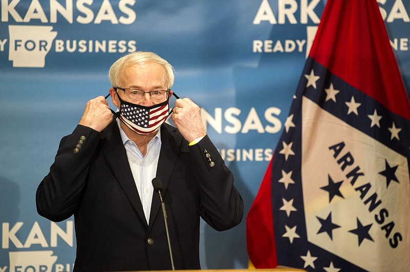 Gov. Asa Hutchinson removes his face mask Friday as he prepares to address the media during an update on Arkansas' response to COVID-19.