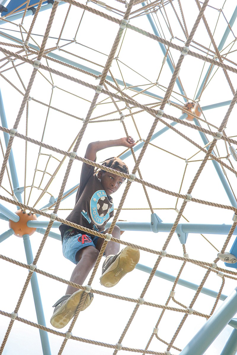 Michael Griffin, 9, climbs a rope structure while on his way to the slide Monday afternoon at Community Park. The large triangular structure is a new addition to the park, which opened to the public this weekend. Besides the climbing structure, a zip line, rope swings, sprayground and new pavilion were added.