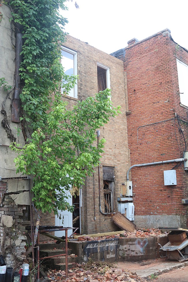 The back of the Regency House building, which is being demolished, is to the left of the tree in this photo. The adjacent building, to the right of the tree with the barred window and old breaker box, was apparently damaged during the Regency House demolition. This adjacent building, located at 114 E. Broad, will likely have to be demolished too because of the recent damage, officials believe.
