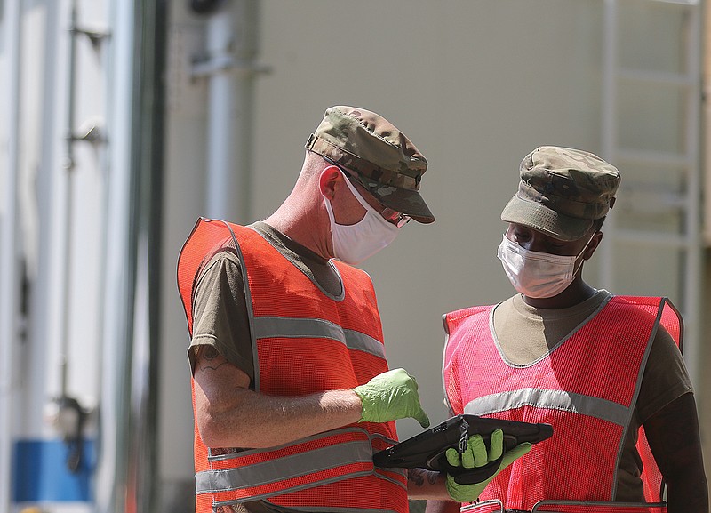 Army National Guard Spc. Matt Umphlett talks to Spc. Sade Frierson while helping usher drivers through the coronavirus testing line Wednesday at the old Cole County Health Department Building at 1616 Industrial Drive. Guard members used tablets to keep track of people being tested.