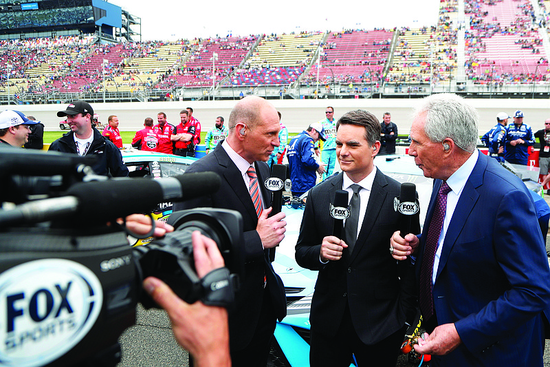 In this June 9, 2019, file photo, Fox Sports broadcasters Adam Alexander (left), Jeff Gordon (center) and Darrell Waltrip are shown on pit road before a NASCAR cup series race at Michigan International Speedway in Brooklyn, Mich.