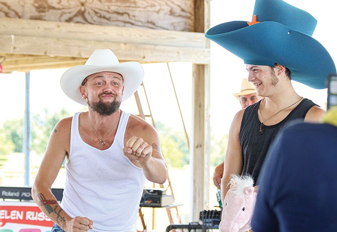 Jason Bennett, left, dances Saturday with Cameron Stornello, right, during the Helen Russell & Company live performance at Russellville's Firework Show festivities. Bennett and Stornello were awarded the "Golden Throne Award," small, plastic golden toilets, for dancing in front of a crowd. Along with the live performance, a cornhole tournament, car show and multiple vendors were available for attendees.