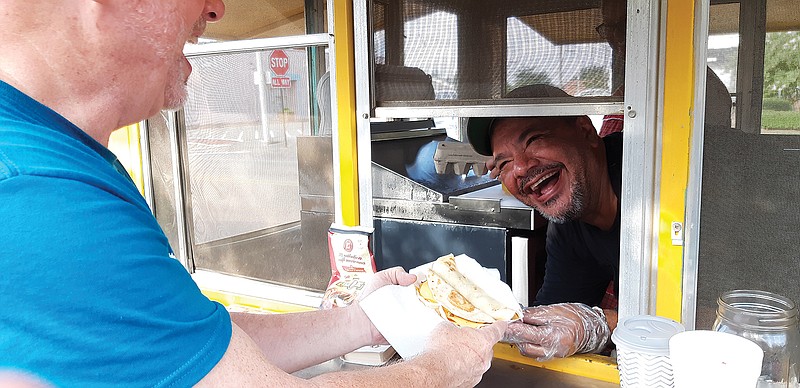 Oscar Hernandez, cook and co-owner of Lot 1621, the bright yellow trailer that made an appearance Saturday at the Texas-side Texarkana Farmers Market, hands Ken Guthrie of Texarkana, Arkansas, his freshly-made breakfast. Fans both new and old lined up for the breakfast which emphasized local ingredients, some from the very farmers working the market that day.