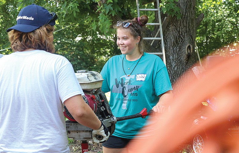 Isabel Phillips, 18, and Ben Turner, 15, prepare to use an auger hole digger Monday to create a series of holes for posts to hold a wooden ramp to the back door of 315 Boonville Road. Volunteers helped clear the home's backyard and prepare for the installment of a handicap ramp during United Methodist's missionary work week. They will continue their work through Wednesday. 