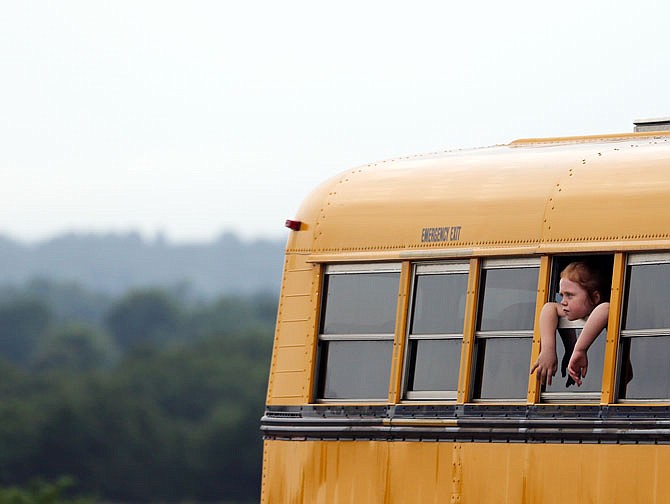 A Blair Oaks student looks out the window of the bus that will take her home from summer school on Wednesday in Wardsville. Rain delayed the students' commute to the busses by a few minutes as Wardsville saw a couple scattered downpours in the afternoon. Summer school for the district ends this week.