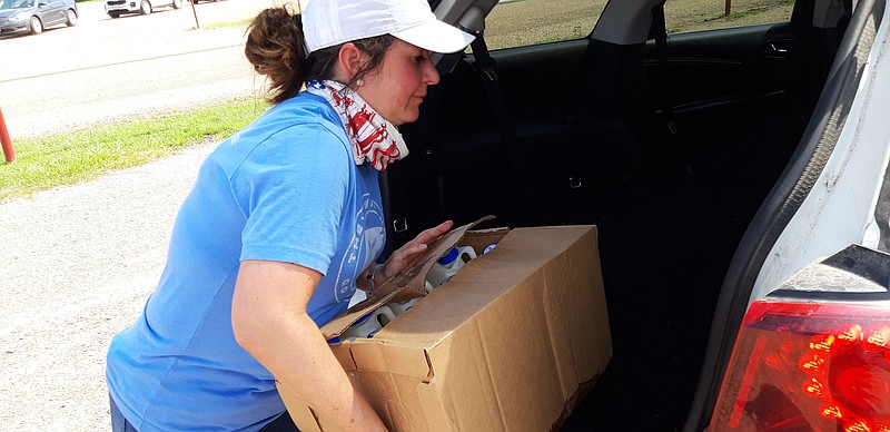 Camille Wrinkle, Harvest Texarkana Regional Food Bank executive director, lends a helping hand as she loads up another car with food. "Events like this are all hands on deck," she said. All families received three boxes of food, which included fruits and vegetables, canned foods, and one box of frozen meat, as well as milk.
