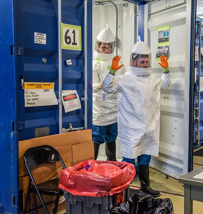 Ryan Swensen is sprayed down with ethanol by Alex Yeaste for added safety as the pair work on the PPE decontamination process. Both work for Battelle Critical Care Decontamination System. The unit serves hospitals, health departments and first responders across the state.