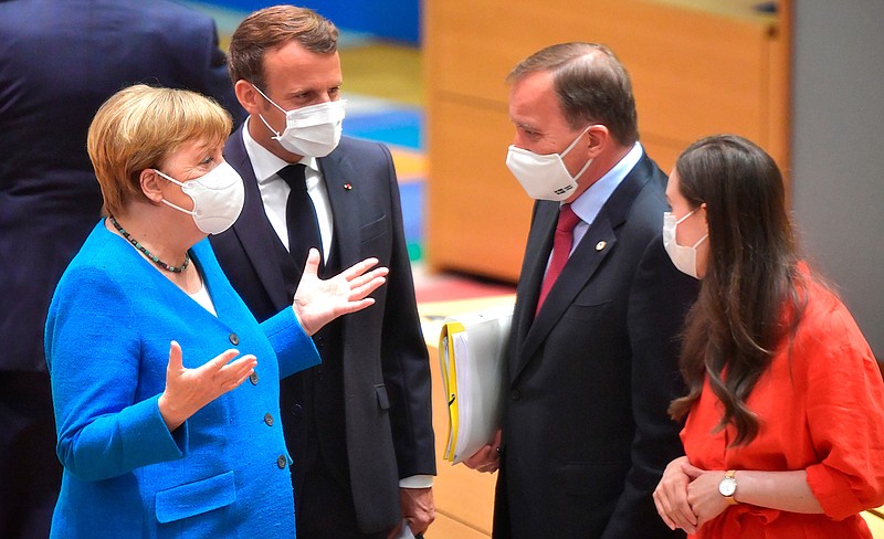 German Chancellor Angela Merkel, left, and French President Emmanuel Macron, second left, speak with Sweden's Prime Minister Stefan Lofven, second right, and Finland's Prime Minister Sanna Marin, right, during a round table meeting at an EU summit in Brussels, Saturday, July 18, 2020. Leaders from 27 European Union nations meet face-to-face for a second day of an EU summit to assess an overall budget and recovery package spread over seven years estimated at some 1.75 trillion to 1.85 trillion euros. (John Thys, Pool Photo via AP)