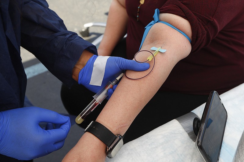 FILE - In this Friday, June 12, 2020 file photo, a woman has blood drawn for COVID-19 antibody testing in Dearborn, Mich. Research published on Tuesday, July 21, 2020 suggests that antibodies the immune system makes to fight the new coronavirus may only last a few months in people with mild illness. (AP Photo/Paul Sancya)