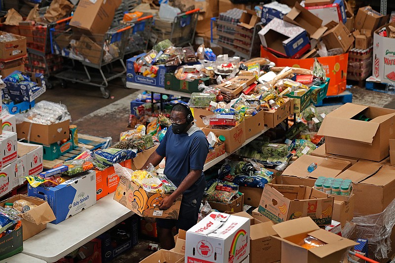 Volunteers distribute food to recipients at the Giving Hope Food Pantry during a food giveaway, which was organized by City Councilmember Cindi Nguyen, in New Orleans, Tuesday, July 21, 2020. The effort is to assist people who have lost income during the COVID-19 pandemic. (AP Photo/Gerald Herbert)