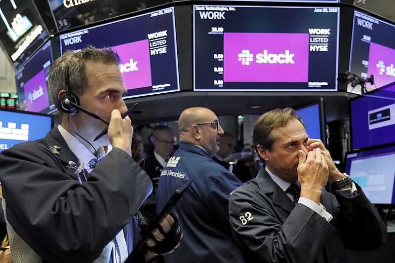 FILE - In this June 20, 2019 file photo, traders Gregory Rowe, left, and Dudley Devine, right, talk into their mobile phones on the floor of the New York Stock Exchange as they wait for the Slack Technologies IPO to begin trading. Workplace chatting service Slack has filed a complaint, Wednesday, July 22, 2020,  in the EU against Microsoft, accusing the software company of anti-competitive behavior. Slack says Microsoft illegally bundles the Microsoft Teams messaging product, which is similar to Slack, into Office 365, its package of email and other widely-used business software.  (AP Photo/Richard Drew, File)