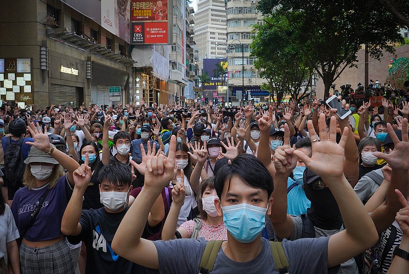 In this Wednesday, July. 1, 2020 file photo, protesters against the new national security law gesture with five fingers, signifying the "Five demands - not one less" on the anniversary of Hong Kong's handover to China from Britain in Hong Kong. Britain's government has announced that it will open a new special pathway to obtaining U.K. citizenship for eligible Hong Kongers from January 2021. The Home Office said Wednesday, July 22, 2020, that holders of the British National Overseas passport and their immediate family members can move to the U.K. to work and study. The change to immigration rules was introduced after China imposed a new, sweeping national security law on Hong Kong. Those eligible can access the British job market at any skill level and without a salary threshold, but won't have access to public funds. (AP Photo/Vincent Yu, file)