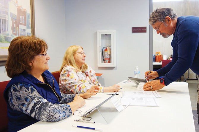 Gerry Hamilton, right, demonstrates how to sign in when casting a vote Tuesday, while regular poll workers Diana Hamilton, left, and Jo Pendergraff look on. This election cycle, the Callaway County Clerk's office is encouraging families, groups, churches and businesses to sign up to keep a polling place free together.