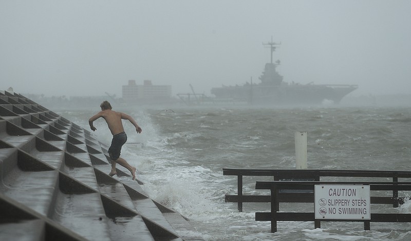 A man jumps from a wave as Hurricane Hanna begins to make landfall, Saturday, July 25, 2020, in Corpus Christi, Texas.   The National Hurricane Center said Saturday morning that Hanna's maximum sustained winds had increased and that it was expected to make landfall Saturday afternoon or early evening.(AP Photo/Eric Gay)