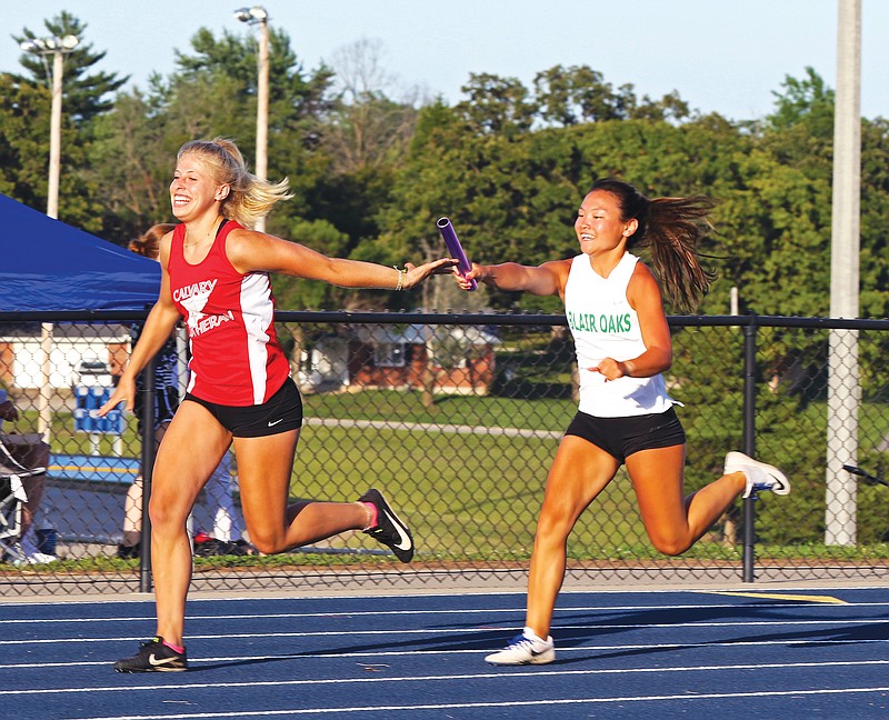 Sarah Johnson of Calvary Lutheran reaches back to receive a handoff from Kaelin Forck of Blair Oaks during a relay Friday at the Russellville Summer Series meet in Russellville.