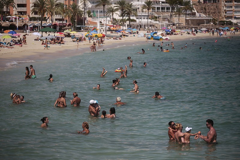 Bathers enjoy the beach Sunday in Palma de Mallorca, Spain. Britain has put Spain back on its unsafe list and announced Saturday that travelers arriving in the U.K. from Spain must now quarantine for 14 days. The move by the UK taken without forewarning has caught travelers off guard. (AP Photo/Joan Mateu)