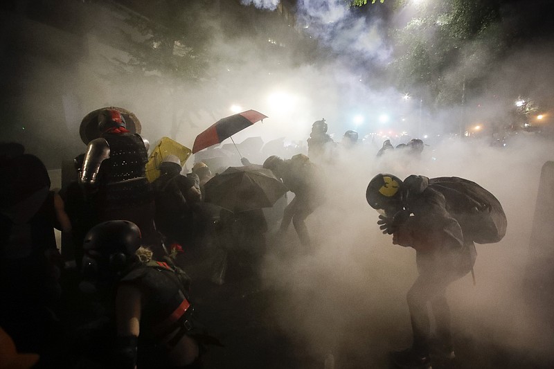 Federal officers launch tear gas at a group of demonstrators during a Black Lives Matter protest at the Mark O. Hatfield United States Courthouse Sunday, July 26, 2020, in Portland, Ore. (AP Photo/Marcio Jose Sanchez)