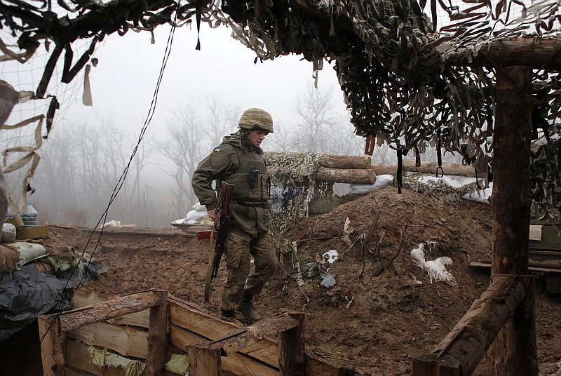 FILE - In this file photo dated Monday, Dec. 9 2019, a Ukrainian soldier takes position on the front line at the town of Novoluhanske in the Donetsk region, Ukraine.   Ukrainian and rebel forces in war-torn eastern Ukraine have started preparing for a “full and comprehensive” ceasefire scheduled to begin at midnight on Monday July 27, 2020. Rebel officials said Sunday they have instructed their troops about the ceasefire and issued a decree banning weapon use, while Ukraine's president said that if upheld, it would “pave the way for implementing other clauses” of the Minsk peace deal. (AP Photo/Vitali Komar, FILE)