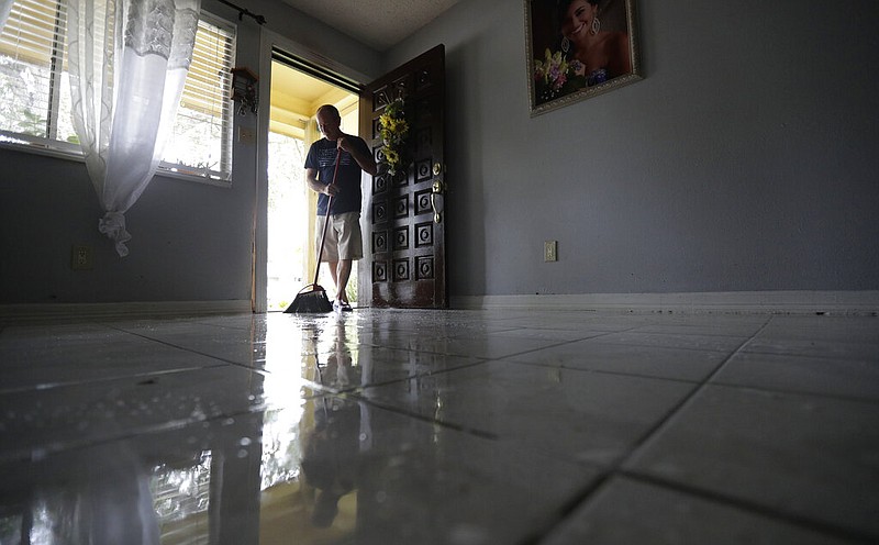 Martin Garcia sweeps water from his home, Monday, July 27, 2020, in Weslaco,Texas. The Garcia's home was flooded by Hurricane Hanna as it passed through the area dropping heavy rains which caused flooding. (AP Photo/Eric Gay)