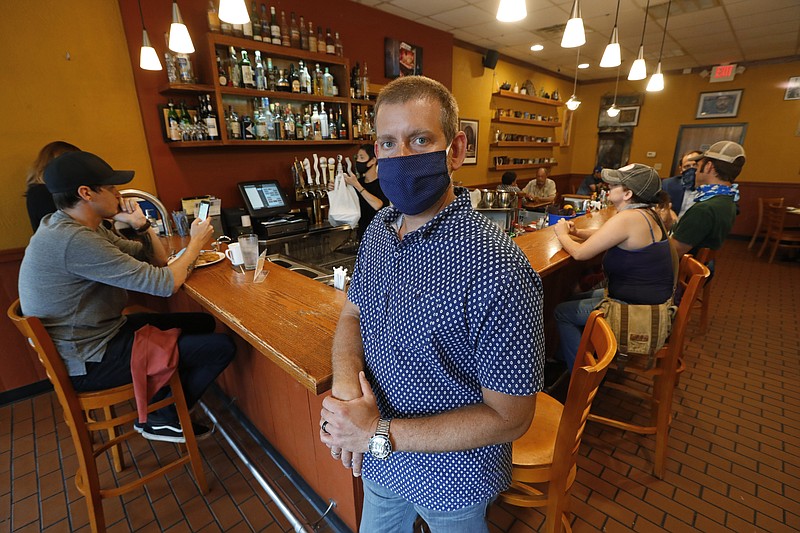 Nick Gavrilides, the owner of the Soup Spoon, poses at one of his two restaurants in Lansing, Mich., Thursday, July 16, 2020. Restaurants, bars and other merchants struggling to stay afloat during the coronavirus pandemic are desperately reaching out for a lifeline from insurers that in turn contend they are being miscast as potential saviors. In one of the first decisions issued on that question, a Michigan state judge sided with an insurer's rejection of a claim for $650,000 for two months of losses that Gavrilides said he suffered at two restaurants. (AP Photo/Paul Sancya)