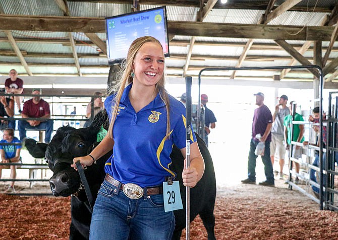 Toni Haselhorst, a Helias Catholic High School junior and member of the Taos Clovers 4-H Club and Nichols Career Cen- ter FFA chapter, laughs Monday with a friend as she enters the 4-H and FFA livestock show ring for the market beef show with her steer, Luke, at the Jefferson City Jaycees Cole County Fair.