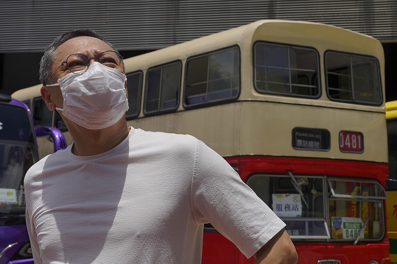 Occupy Central leader Benny Tai stands in front of a vintage double-deck bus used as a polling center for an unofficial "primary" for pro-democracy candidates ahead of legislative elections in Hong Kong Saturday, July 11, 2020. Tai, a professor and leading figure in Hong Kong's political opposition has been fired from his university job following China's passage of a sweeping new national security law. (AP Photo/Vincent Yu)
