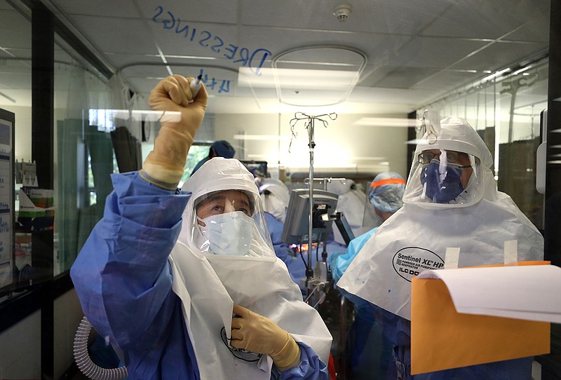 (EDITORIAL USE ONLY) A nurse writes a note on a window as a team of doctors and nurses performs a procedure on a coronavirus COVID-19 patient in the intensive care unit (I.C.U.) at Regional Medical Center on May 21, 2020 in San Jose, California. Frontline workers are continuing to care for coronavirus COVID-19 patients throughout the San Francisco Bay Area. Santa Clara county, where this hospital is located, has had the most deaths of any Northern California county, and the earliest known COVID-19 related deaths in the United States. (Justin Sullivan/Getty Images/TNS)