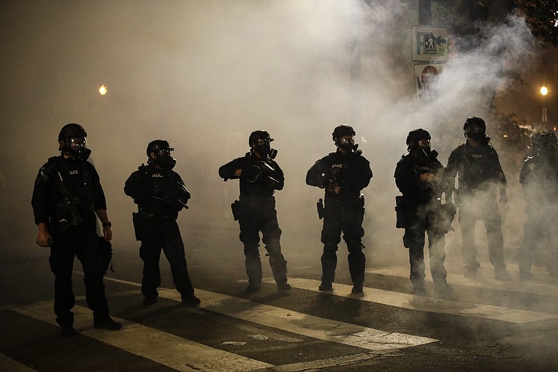 Federal officers are surrounded by smoke as they push back demonstrators during a Black Lives Matter protest at the Mark O. Hatfield United States Courthouse Wednesday, July 29, 2020, in Portland, Ore. (AP Photo/Marcio Jose Sanchez)
