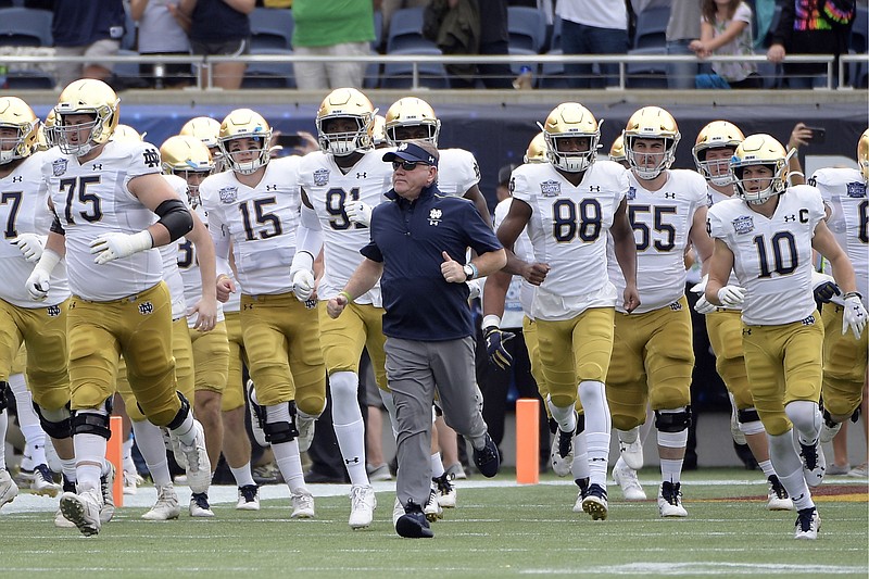 In this Dec. 28, 2019, file photo, Notre Dame head coach Brian Kelly runs onto the field with his players before the Camping World Bowl against Iowa State in Orlando, Fla.
