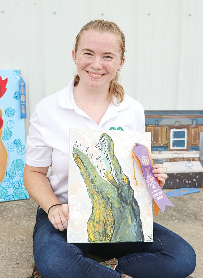 Jessica Koenigsfeld, Helias Catholic High School sophomore and St. Martins 4-H member of five years, smiles for a photo Monday outside of the 4-H exhibition hall with her original painting of an alligator at the Jefferson City Jaycees Cole County Fair. Koenigsfeld entered five paintings through 4-H this year, each receiving a blue ribbon.