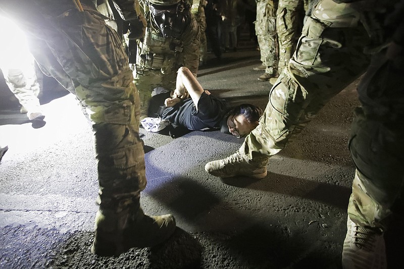 FILE - In this July 29, 2020, file photo, federal agents arrest a demonstrator during a Black Lives Matter protest at the Mark O. Hatfield United States Courthouse in Portland, Ore. An Associated Press analysis of more than 200 arrests shows that even those accused of breaking the law during the nightly rallies don’t neatly fit into President Donald Trump’s depiction of protesters as “anarchists and agitators.” (AP Photo/Marcio Jose Sanchez, File)