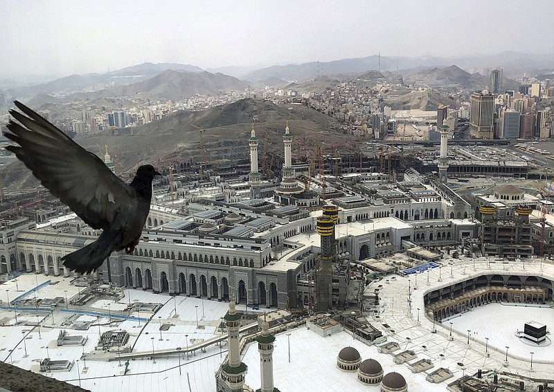 A pigeon flies over the site of the Grand Mosque that is empty due to the coronavirus prevention procedures, on the first day of the annual hajj that normally draws millions of faithful, in the Muslim holy city of Mecca, Saudi Arabia, Wednesday, July 29, 2020. A unique and scaled-down hajj started on Wednesday. (AP Photo)