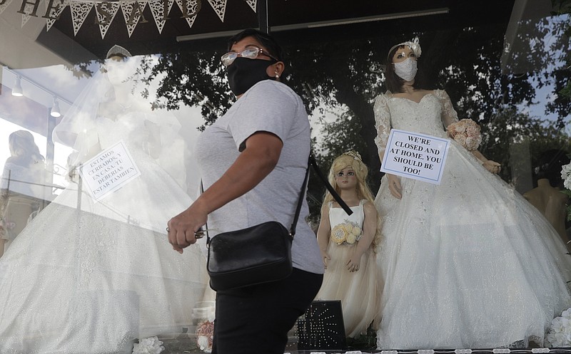 A shopper passes a display window with mask covered mannequins at a dress store, Thursday, July 30, 2020, in McAllen, Texas. (AP Photo/Eric Gay)