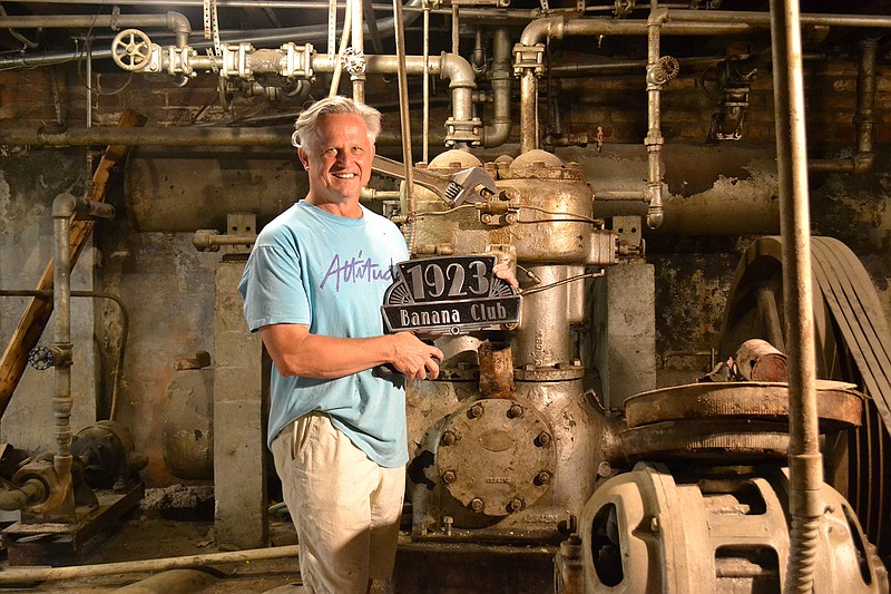 David Peavy, owner of the 1894 City Market, poses in the basement with a sign that reads "1923 Banana Club." He had the sign made in anticipation of a club he will open there. (Photo by Kate Stow)