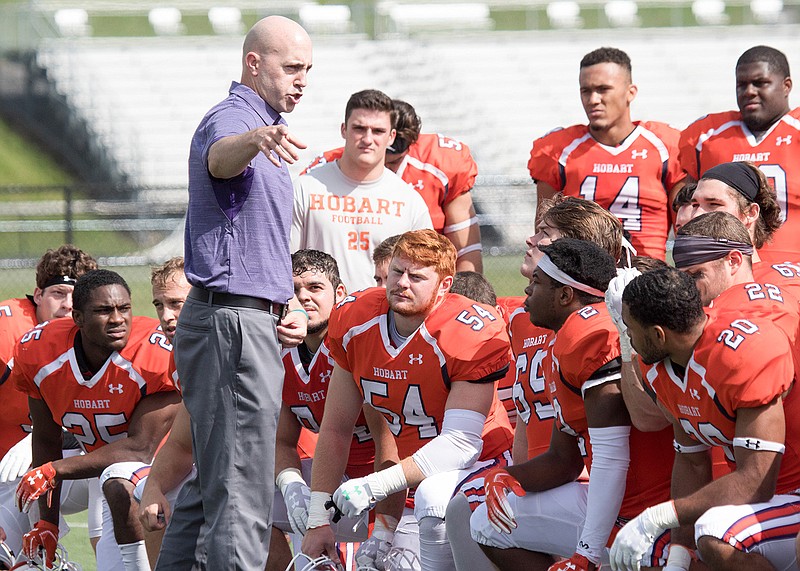 In this image provided by Hobart and William Smith Colleges, Hobart head coach Kevin DeWall addresses his team following the Statesmen's 33-7 win over No. 13 Brockport to open the 2019 season on Sept. 7, 2019, in Geneva, N.Y. There will be no pregame Victory Walk or singing of the alma mater after wins at Hobart College's 3,000-seat Boswell Field this fall. The coronavirus pandemic has led to the cancellation or postponement of more than 1,800 games across the NCAA, more than 1,000 in Division III. (Mary Mazzarella/Hobart and William Smith Colleges via AP)