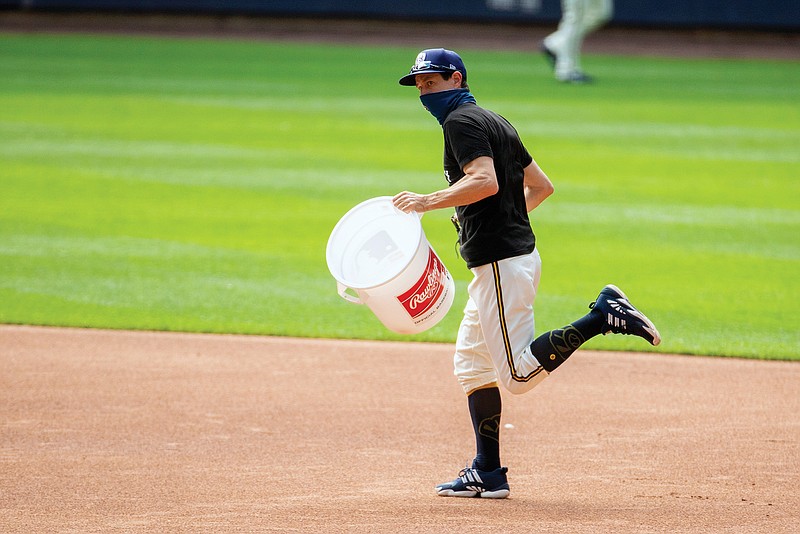 Brewers manager Craig Counsell runs with a bucket after it was announced Friday's game with the Cardinals was called off in Milwaukee.