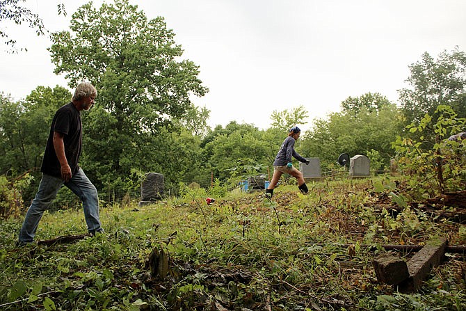 As mosquitoes buzzed and spiders scuttled underfoot, volunteers trekked through the cemetery and cleared thick brush and fallen trees.
