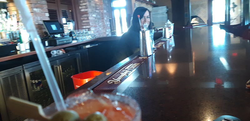 Laryn Furlow, bar manager of Crossroads, gazes from behind a Bloody Mary of her own making. As a veteran barkeep, she brings many cocktail recipes of her own creation at Crossroads.