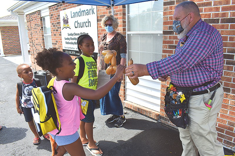 Elizabeth Mensah, 8, is all smiles as she gets a balloon dog Sunday from magician/balloon artist David Scott during the Back-to-School Block Party at Landmark Church. Behind Elizabeth are her brothers Daniel, 5, and Samuel, 9.