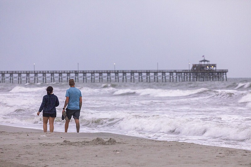 Walkers stroll past Cherry Grove pier at dawn in North Myrtle Beach. Tropical Storm Isais is moving up the east coast and is expected to make landfall near Myrtle Beach, S.C., on Monday, Aug. 3, 2020. (Jason Lee/The Sun News via AP)