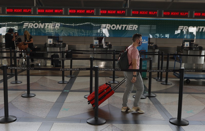 FILE - A lone traveler heads to the ticketing counter of Frontier Airlines in the main terminal of Denver International Airport on July 22, 2020, in Denver.   Hotel and home-sharing reservation site Booking.com plans to lay off 25% of its workforce, or more than 4,000 people, due to the impact of the new coronavirus on travel. Connecticut-based parent company Booking Holdings said Tuesday, Aug. 4,  that the layoffs will begin next month.  (AP Photo/David Zalubowski, File)