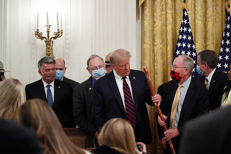 Sen. Lamar Alexander, R-Tenn., gives President Donald Trump a walking stick during a signing ceremony for H.R. 1957  "The Great American Outdoors Act," in the East Room of the White House, Tuesday, Aug. 4, 2020, in Washington. (AP Photo/Alex Brandon)