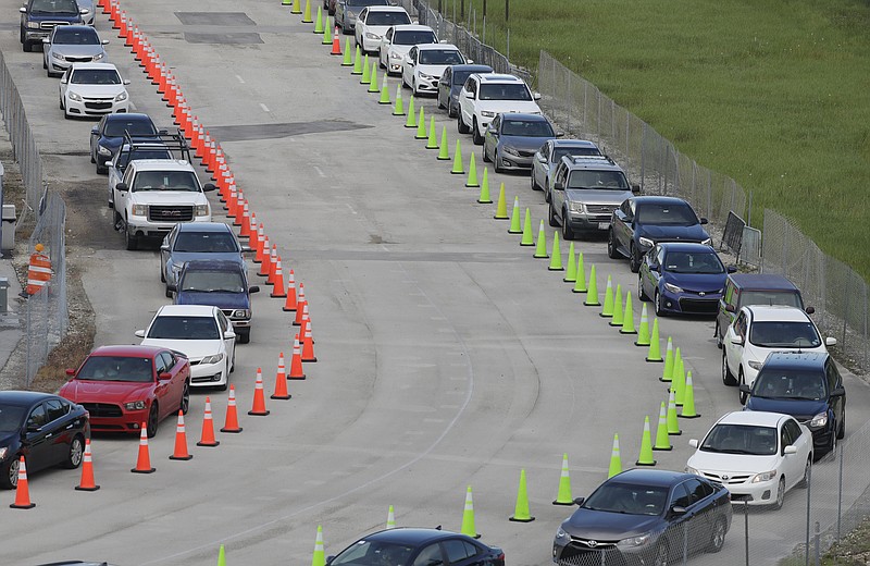 Cars wait in lines, Wednesday, Aug. 5, 2020, at a COVID-19 testing site outside Hard Rock Stadium in Miami Gardens, Fla. State officials say Florida has surpassed 500,000 coronavirus cases. Meanwhile, testing is ramping up following a temporary shutdown of some sites because of Tropical Storm Isaias. (AP Photo/Wilfredo Lee)